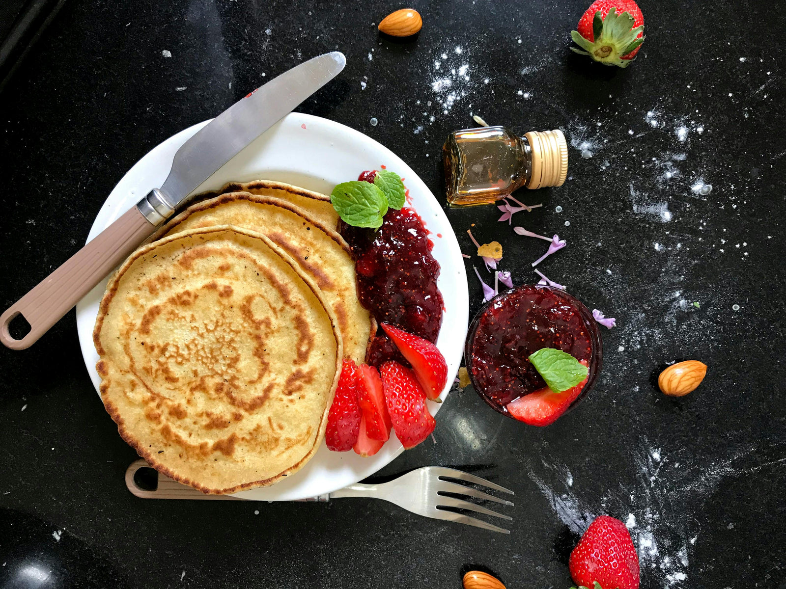 Delightful pancakes served with fresh strawberries and jam