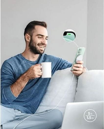 Man sitting on couch using phone with Anker magnetic wireless charger attached for fast charging