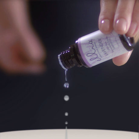 Close-up of a hand pouring lavender essential oil onto the Homedics Ellia Harmony diffuser