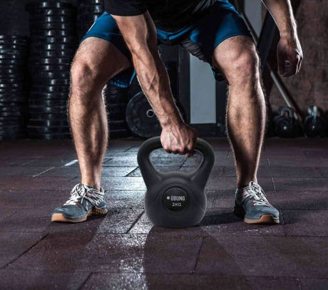 Calitek 2kg fitness kettlebell held by person in gym wearing athletic shoes and shorts
