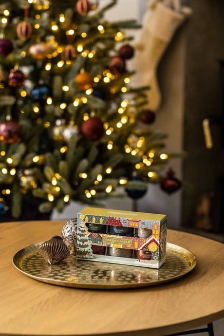 Yankee Candle Christmas gift set displayed on gold tray with decorated Christmas tree in background