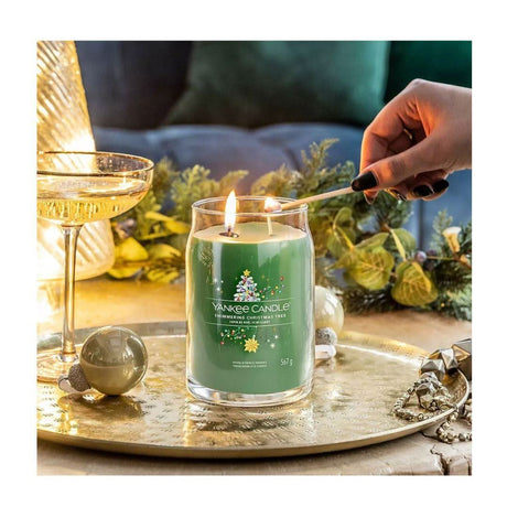 Yankee Candle Christmas Tree scent green holiday candle being lit on a gold tray with festive decorations