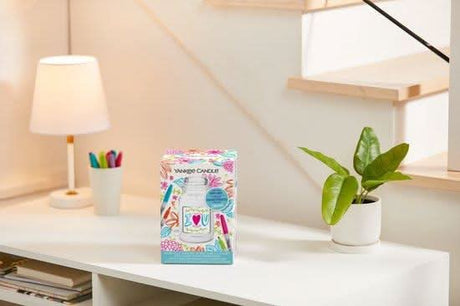 Custom Yankee Candle gift box with colorful design displayed on a white desk with lamp and potted plant