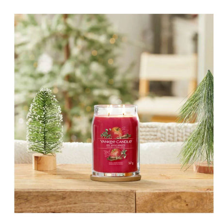 Yankee Candle Red Apple Wreath scented red candle with two wicks on wooden table with holiday decor
