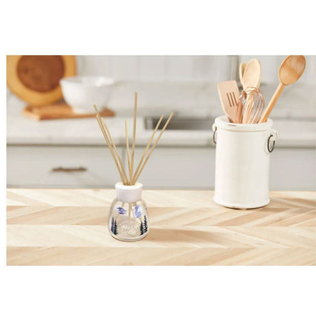 Yankee Candle reed diffuser with wooden reeds on kitchen countertop next to utensil holder