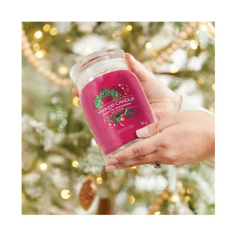 Yankee Candle Sparkling Winterberry large jar candle held in hands with blurred holiday lights background