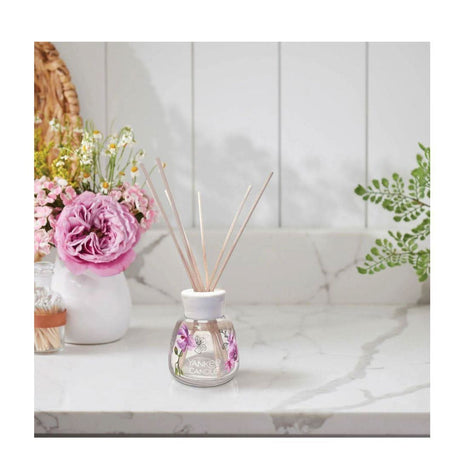 Yankee Candle wild orchid reed diffuser on marble countertop with floral decor background
