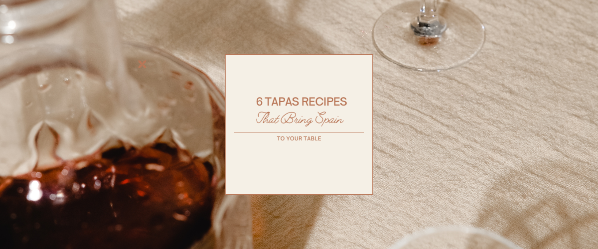 Close-up of a table setting with wine and a card featuring authentic Spanish tapas recipes