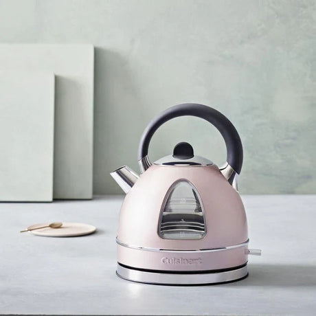 Sleek pink Cuisinart electric kettle with black handle and stainless steel accents on a gray countertop