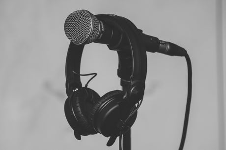 Black microphone with headphones hanging on stand representing home audio systems setup