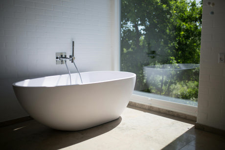 Modern bathroom with a freestanding white bathtub and luxury bathroom fixtures near a large window