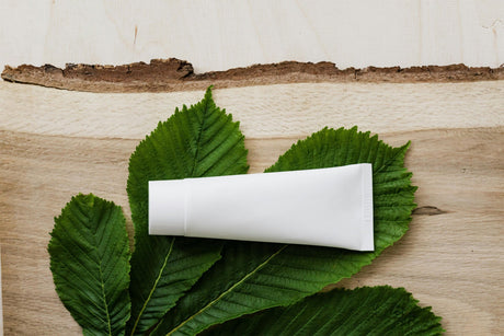 Blank white skincare tube on green leaves representing affordable skincare products for daily beauty routine