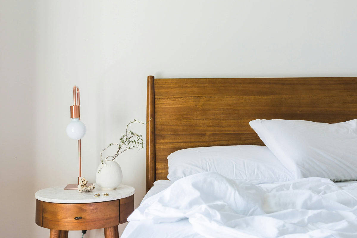 Cozy bedroom setup with wooden bed frame and side table showcasing affordable bedroom furniture