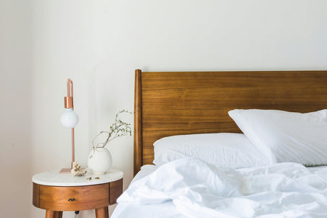 Cozy bedroom setup with wooden bed frame and side table showcasing affordable bedroom furniture
