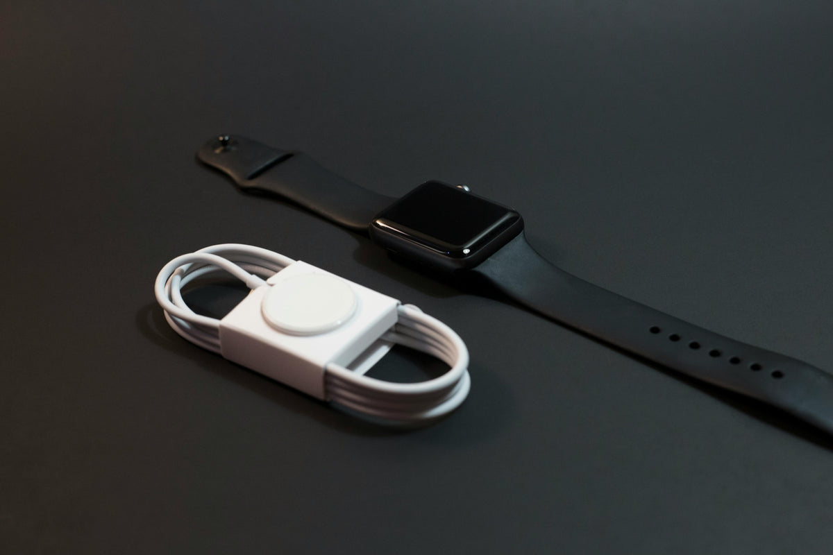 Affordable tech chargers including a wireless charger cable and a black smartwatch on a dark surface