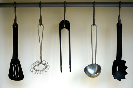 Collection of kitchen gadgets online including spatula, whisk, tongs, ladle, and pasta server hanging on a rack