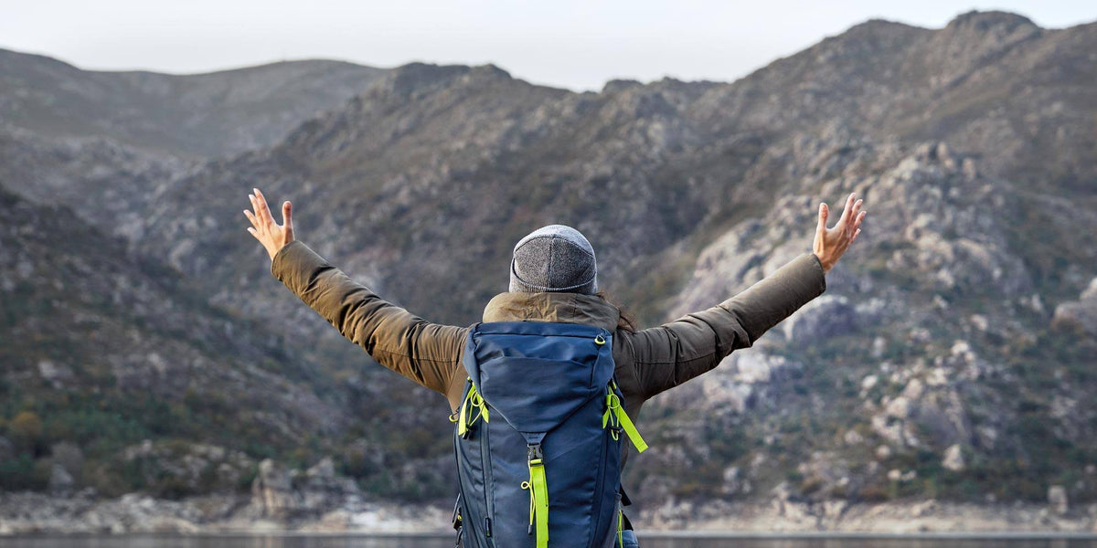 Hiker with backpack enjoying mountain view representing outdoor living essentials collection
