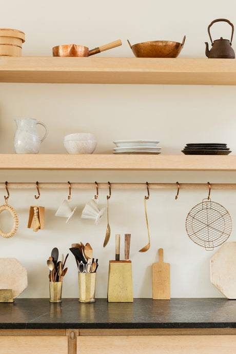 Organized kitchen shelves and countertop displaying new home essentials including cookware, utensils, plates, and kitchen tools