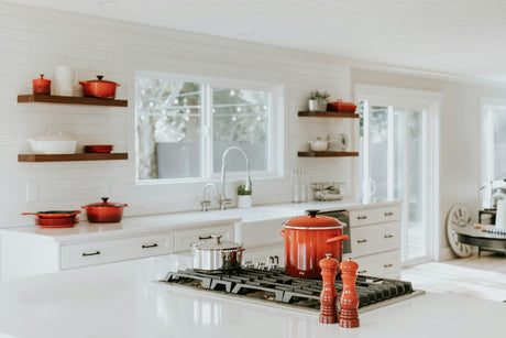 Modern white kitchen with red cookware and appliances showcasing homeware deals online
