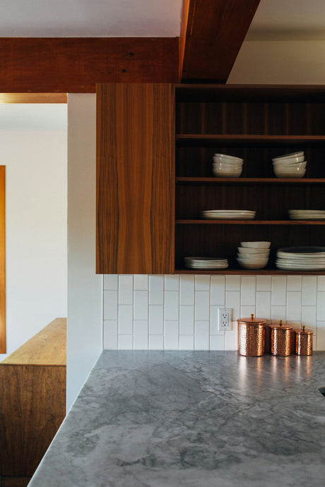 Modern kitchen featuring marble countertops with new homeware arrivals April including white dishes and copper canisters