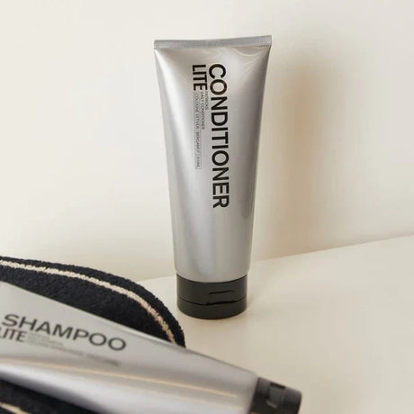 Silver conditioner and shampoo tubes for the best hair products for home use on a white surface with a black towel