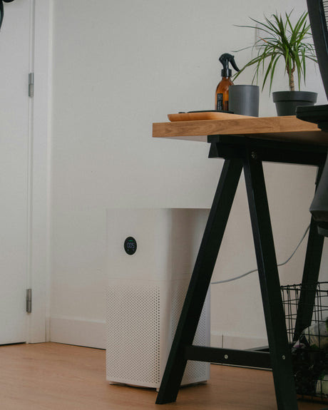 Whirlpool home appliances air purifier with HEPA filter placed in a modern indoor room near a wooden desk