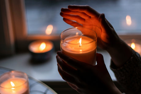 Hands warming near lit luxury scented candles for home creating cozy and inviting ambiance