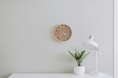 Minimalist home essentials under 7 pounds including wall clock, white desk lamp, and small potted plant