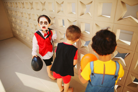 Boys wearing boys fancy dress costumes including spooky and superhero styles playing with balloons at a party