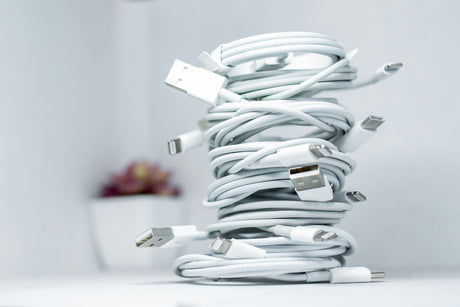 Stack of white Anker charging cables with USB and Lightning connectors neatly coiled on a white surface
