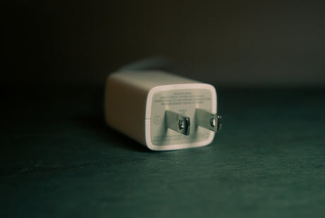 Close-up of a white universal power adapters plug lying on a dark surface to charge devices