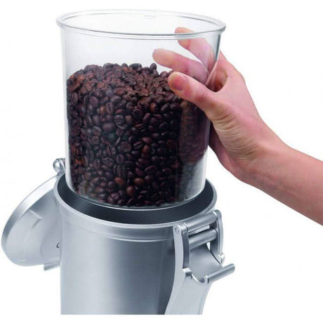 Stainless steel coffee canister with airtight lid holding fresh coffee beans being lifted by hand
