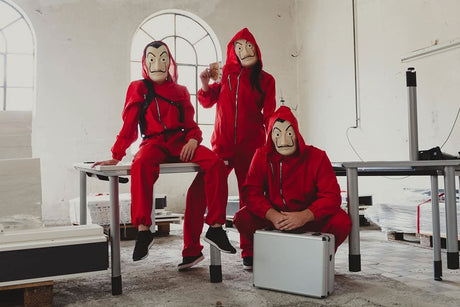 Three people wearing adult money heist jumpsuit with red hooded suits and Salvador Dalí masks indoors