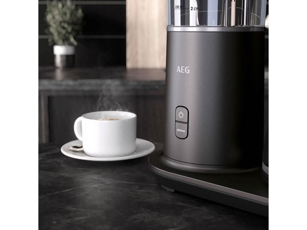 AEG coffee machine 1600W black model with power and aroma buttons on kitchen counter next to steaming cup of coffee