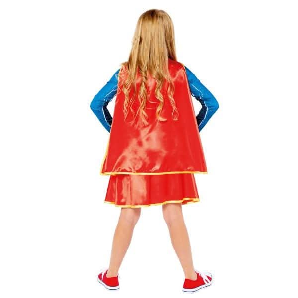 Child wearing a Sustainable Supergirl costume for kids with red cape and blue top from Fancy Dress