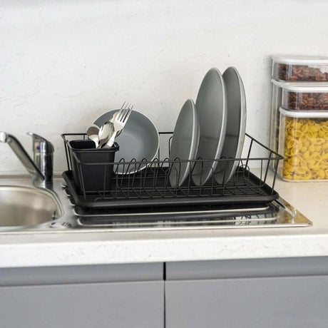 Black anti rust kitchen dish rack from CLICKK Home Store holding gray plates and utensils on a kitchen sink