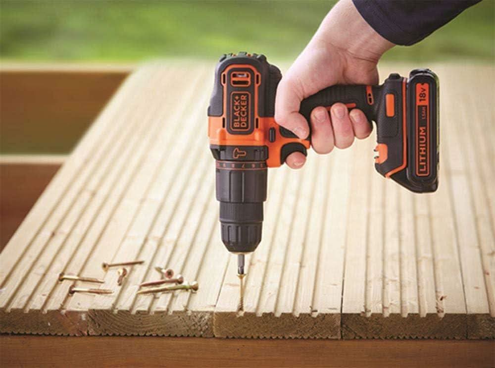 Black and Decker cordless hammer drill being used to drill into wooden planks with screws nearby