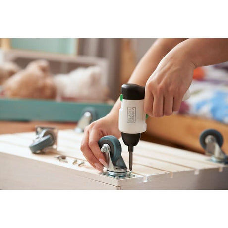 Person using Black and Decker cordless screwdriver to attach caster wheels to wooden board