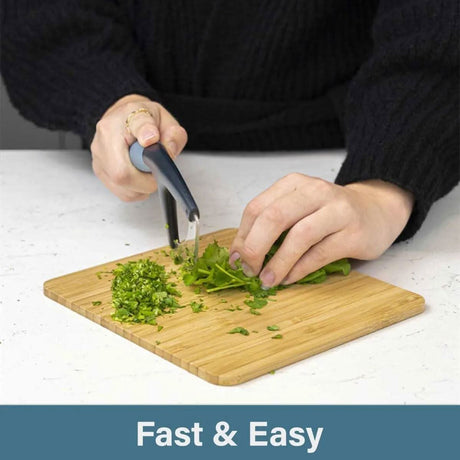 Calitek herb chopper mezzaluna chopping fresh herbs on a wooden cutting board for fast and easy use