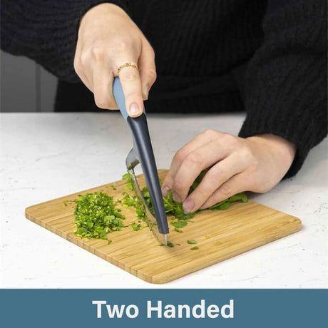 Calitek herb chopper mezzaluna with two-handed grip chopping fresh herbs on wooden board
