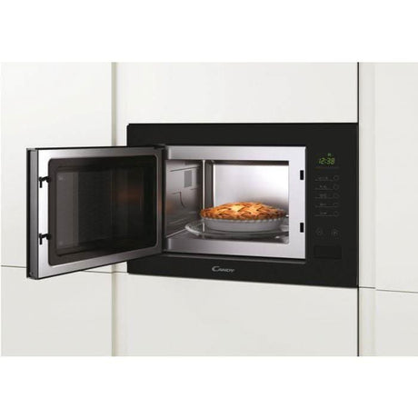Candy built-in microwave with grill open showing a pie inside in a modern kitchen