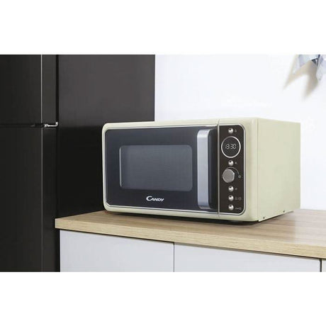 Retro microwave oven beige with digital display and control knobs on wooden kitchen countertop