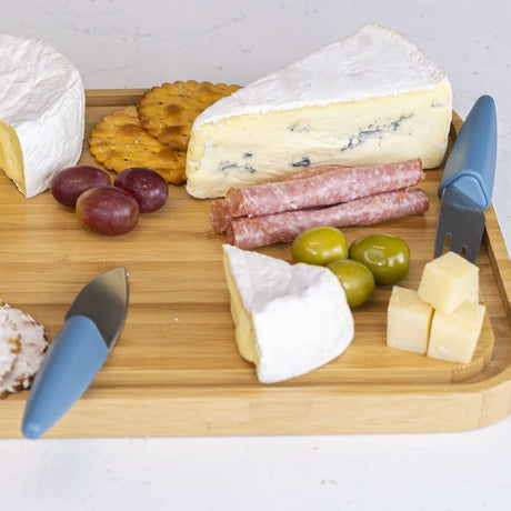 Cheese knife set with stand by Calitek displayed with cheese, crackers, grapes, olives, and sliced meat on a wooden board