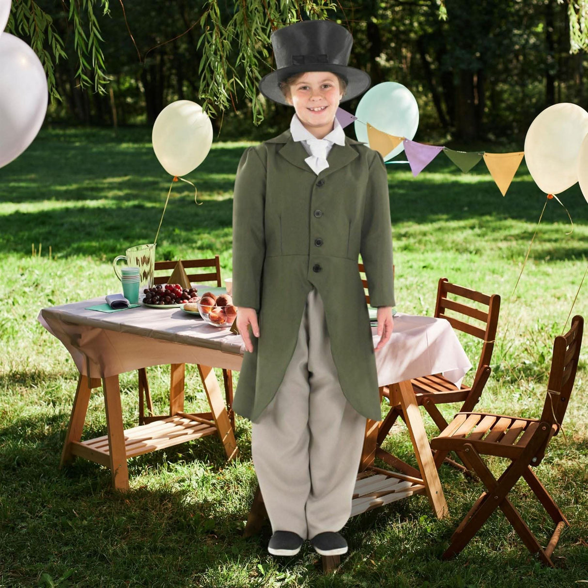 Child wearing a child regency boy costume with green coat and top hat standing outdoors near a decorated table