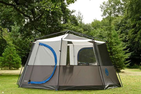 8 person family camping tent set up outdoors in a green forest area with large windows and a spacious interior