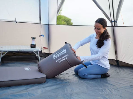 Woman setting up Coleman self inflating sleeping mat inside a tent for camping comfort