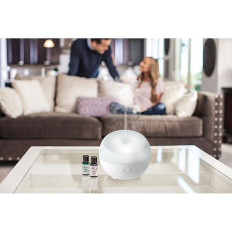 Homedics color changing essential oil diffuser emitting mist in a cozy living room setting