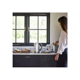 Woman using Cuisinart 4 slice toaster on kitchen counter next to electric kettle and bread