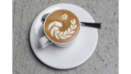 DeLonghi porcelain cappuccino cups with cappuccino and latte art on white saucer and spoon