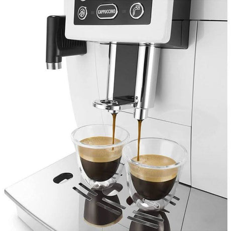 DeLonghi double wall espresso glasses filled with espresso under a coffee machine brewing two shots